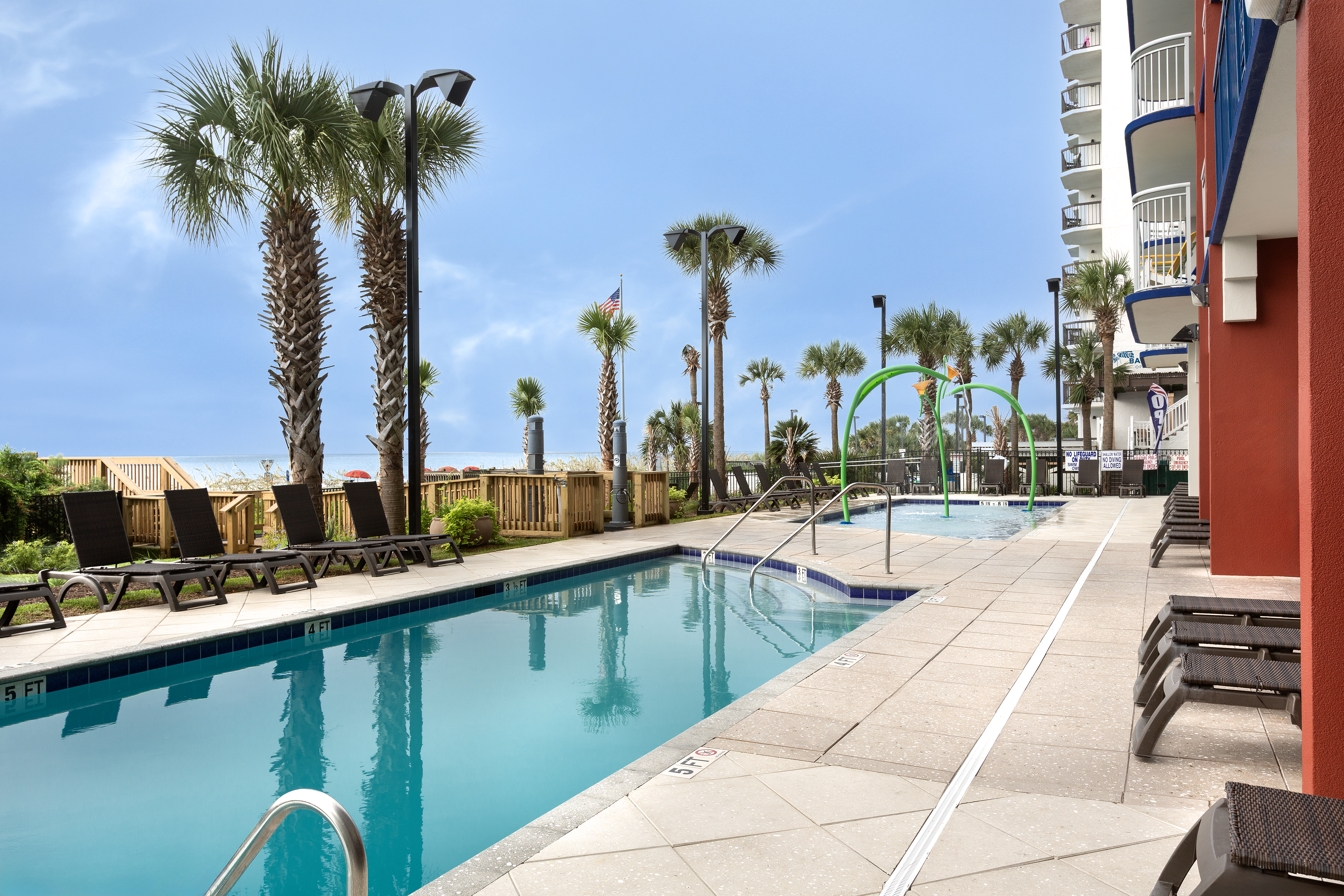 A swimming pool with lounge chairs and palm trees