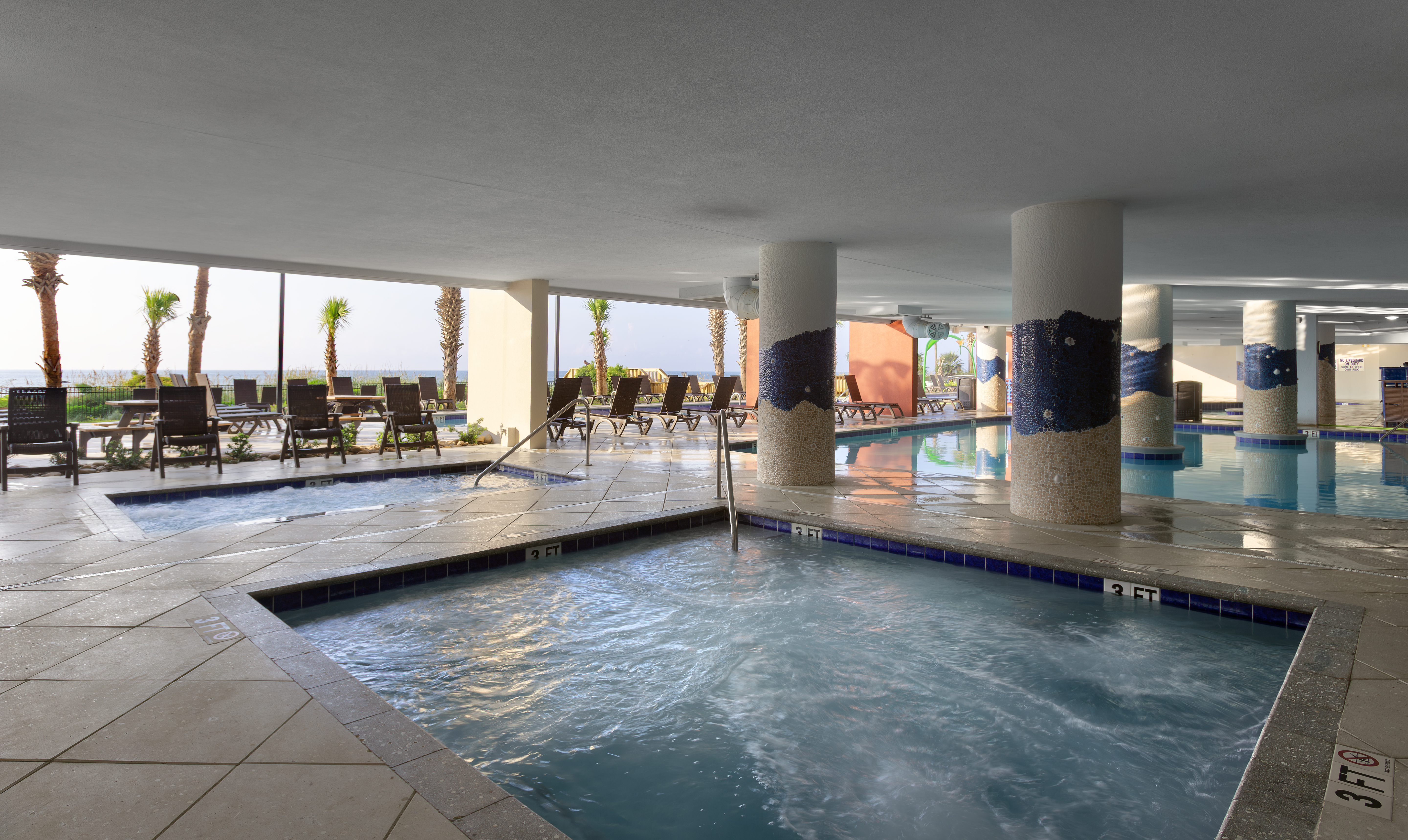 a large indoor pool with a hot tub and lounge chairs