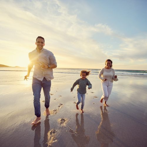 Mother,,Father,And,Child,Run,On,Beach,On,Holiday,,Summer